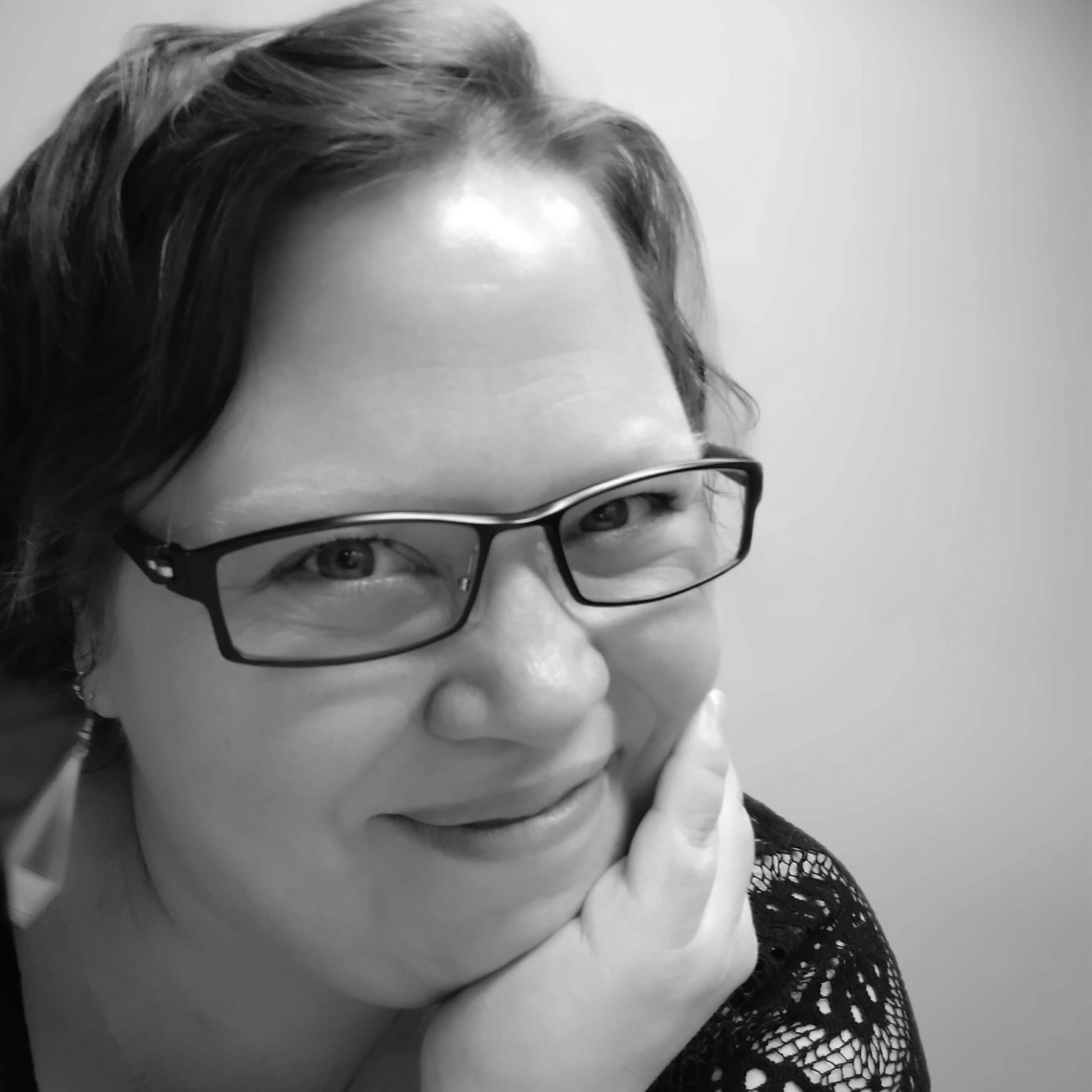Black and white photograph of author, editor and publisher, Kate Cuthbert. She is leaning on her hand, looking into the camera.